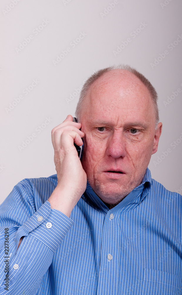 Older Balding Man in Blue Shirt Unhappy on Phone Older Balding Man in Blue Shirt Unhappy on Phone