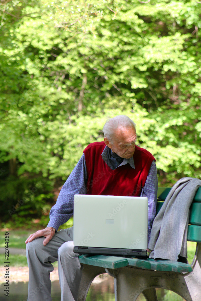 Alter Mann arbeitet mit dem Laptop im Grünen Alter Mann arbeitet mit dem Laptop im Grünen