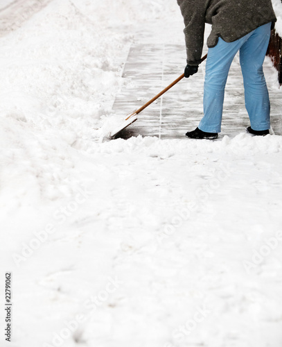 Woman shoveling snow from the sidewalk in front of his house aft