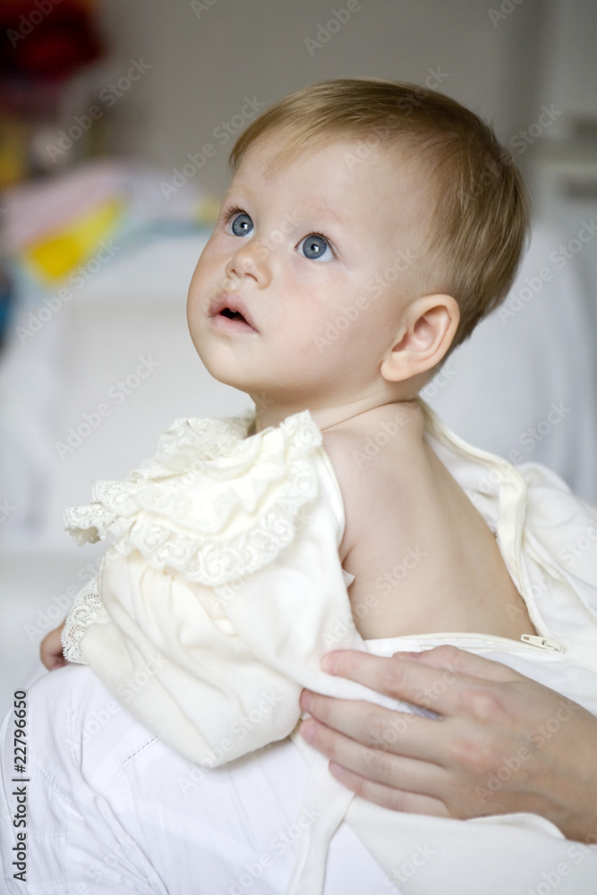 Cute baby sitting on a bed dressed in a bodysuit Cute baby sitting on a bed dressed in a bodysuit