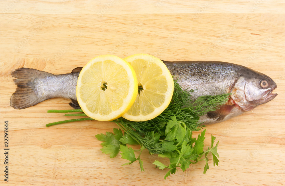 Raw fish with lemon and parsley on wooden background Raw fish with lemon and parsley on wooden background