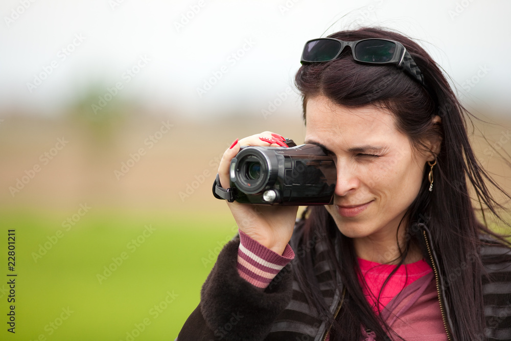 Young lady using video camera outdoors Young lady using video camera outdoors
