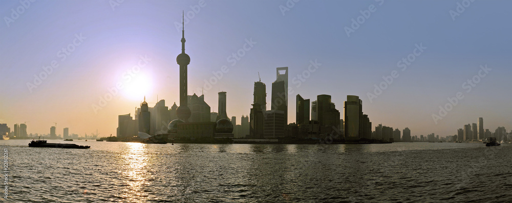 The sun rises behind the skyline of Shanghai's Pudong district