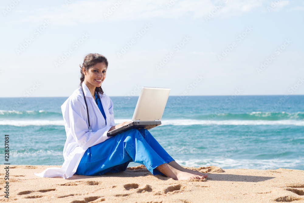 pretty indian intern using laptop on beach