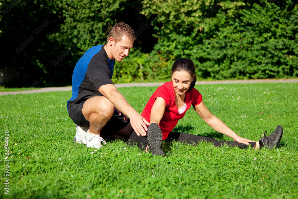 Frau dehnt sich mit Hilfe ihres Personal Trainers Frau dehnt sich mit Hilfe ihres Personal Trainers