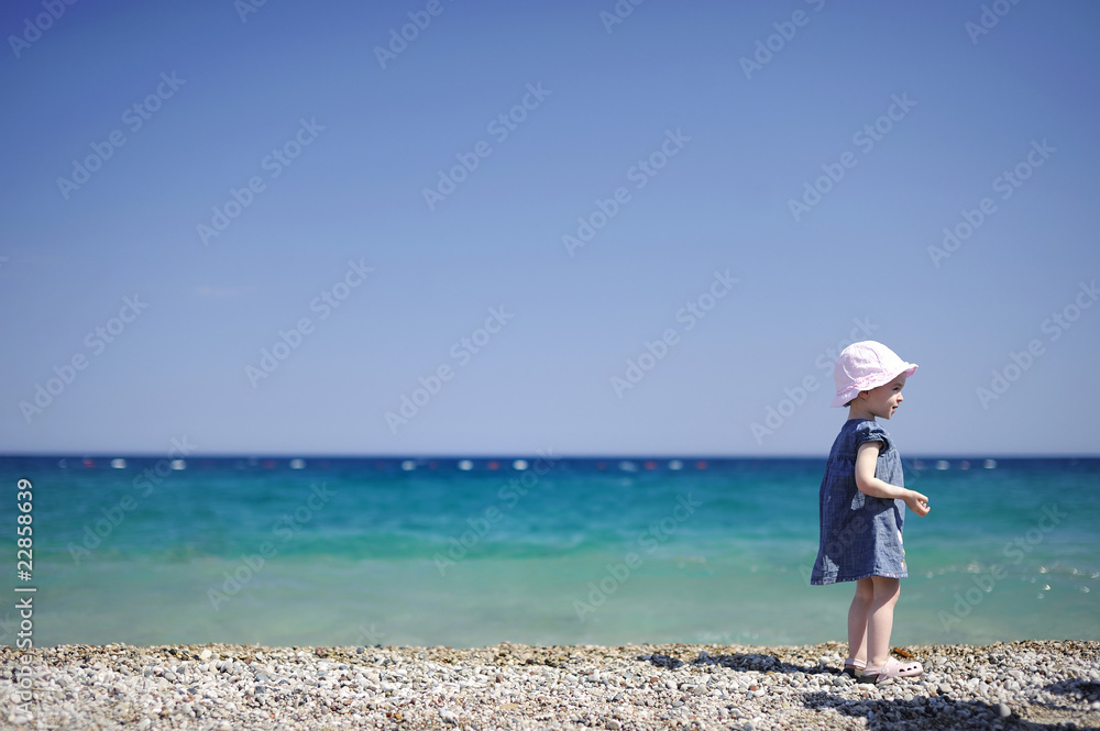 Adorable girl on a pebble beach