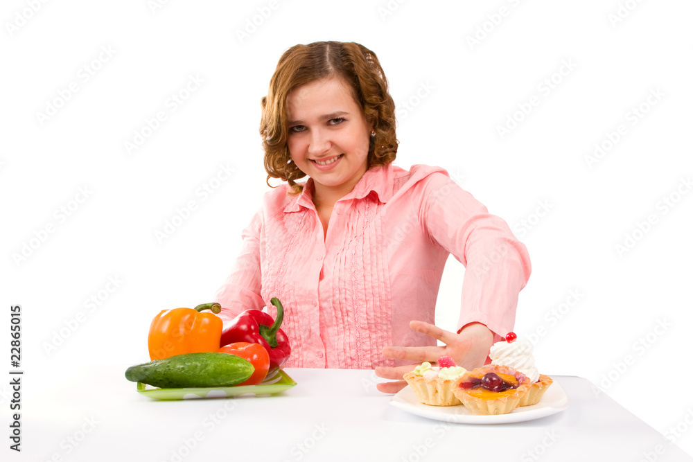 Woman makes choice of cakes and vegetables Woman makes choice of cakes and vegetables
