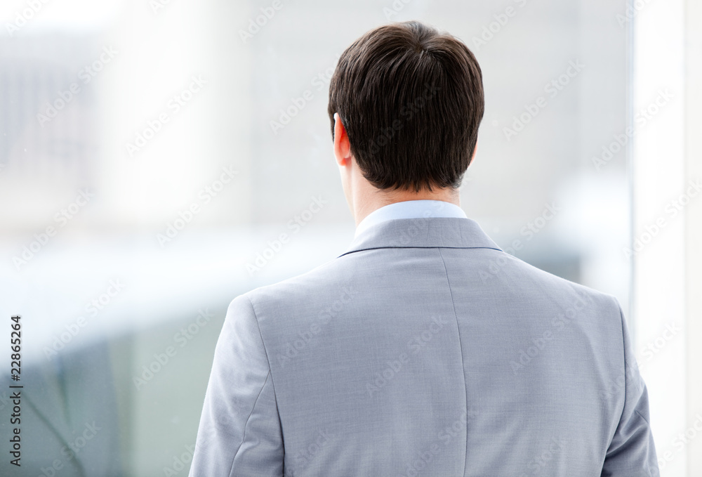 Confident businessman looking through a window of the building Confident businessman looking through a window of the building