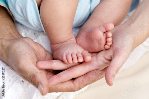 Parental hands holding legs of the baby