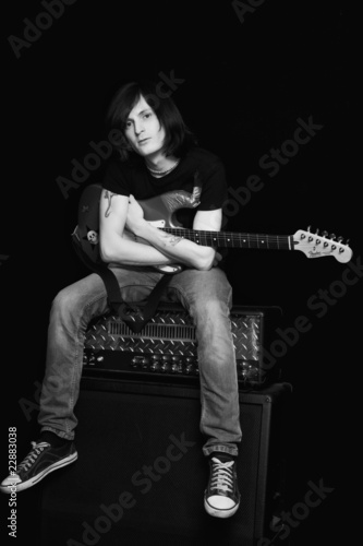 The guitarist with a guitar sitting on musical equipment