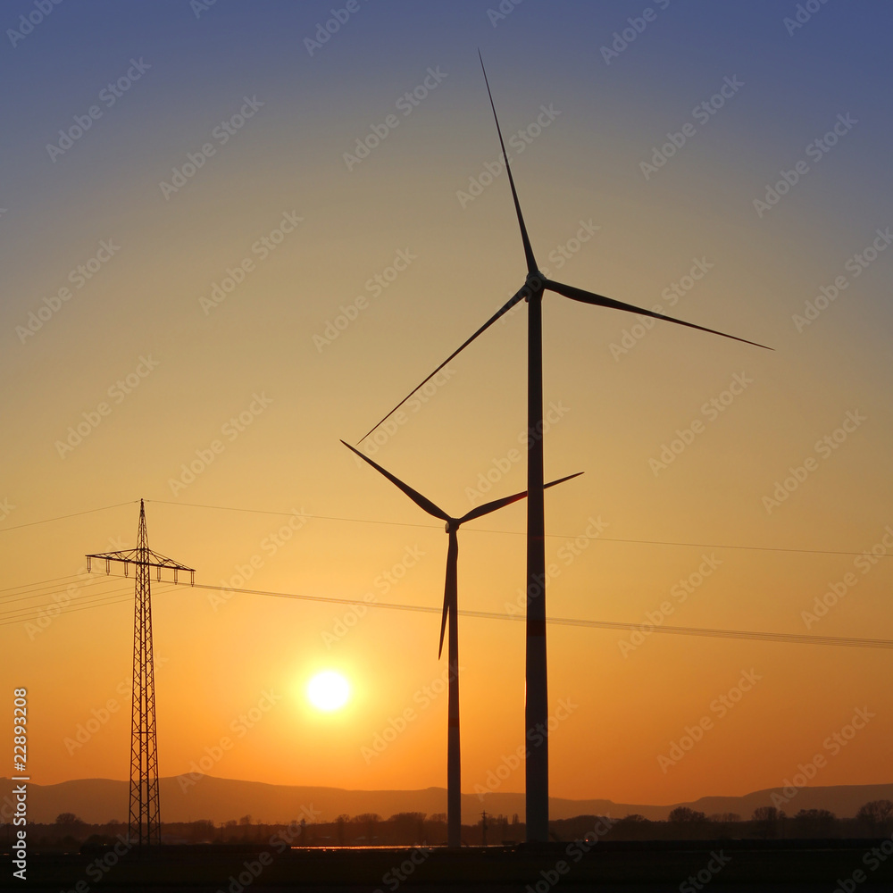 Windräder und Strommast im Sonnenuntergang
