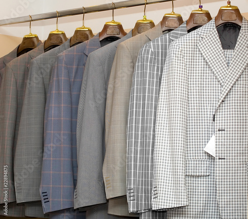 A row of designer suits hanging in a menswear store.