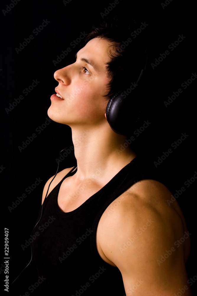 Young Man listening to music with headphones, on black backgroun