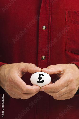 Man holds white egg with the British pound symbol (£) written on