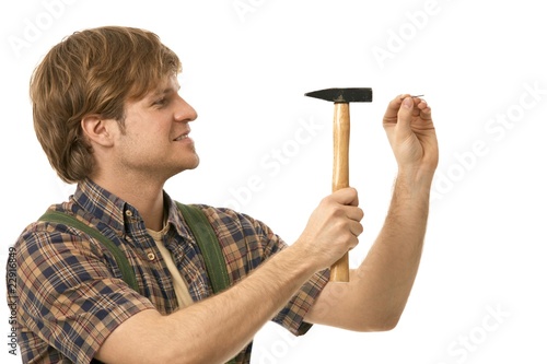 Fotografie, Obraz Young man hammering nail