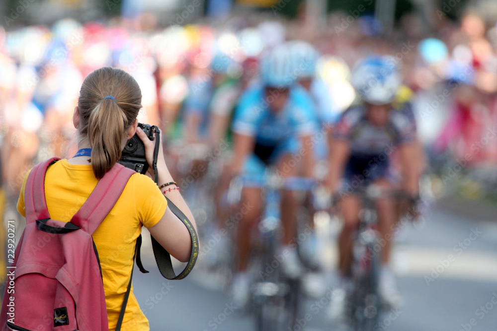 Eine junge Frau mit Kamera fotografiert ein Radrennen in Nürnberg