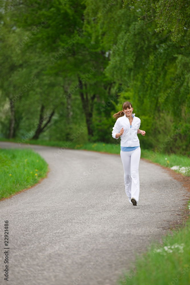 Jogging - sportive woman running on road in nature Jogging - sportive woman running on road in nature