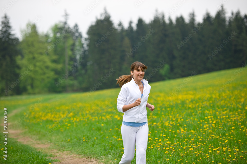 Jogging - sportive woman running in park with dandelion Jogging - sportive woman running in park with dandelion