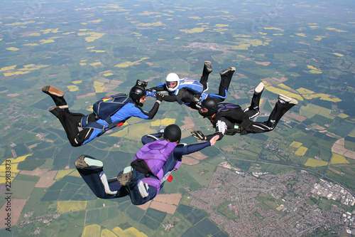 Four skydivers in freefall holding hands