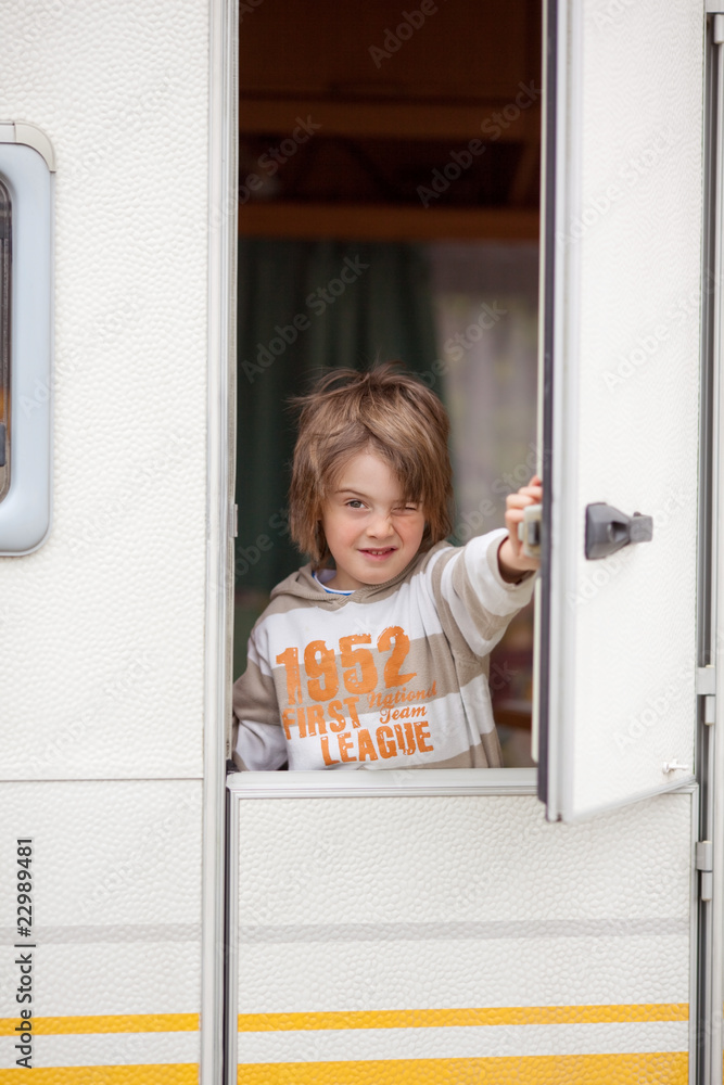 kleiner junge schaut aus dem wohnwagen