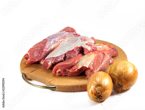 red raw meat and onion over white on wooden plate