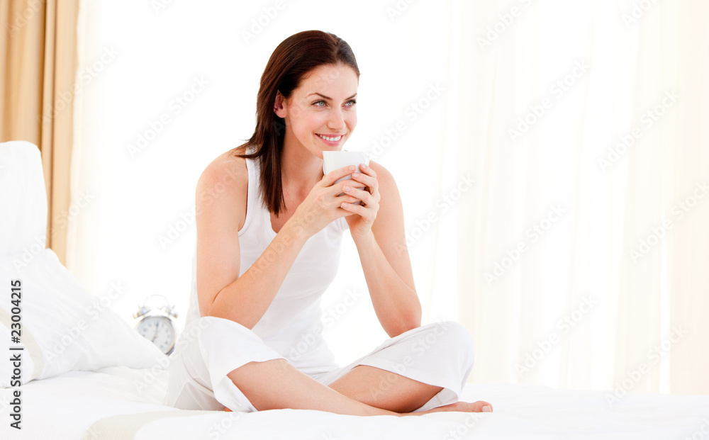 Beautiful woman drinking a coffee sitting on her bed Beautiful woman drinking a coffee sitting on her bed