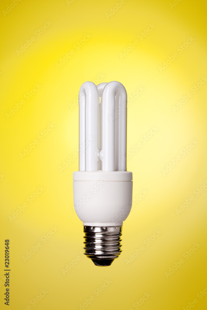 Small energy saving lamp on yellow background Small energy saving lamp on yellow background