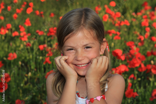 Pretty young girl laughing in a poppy field