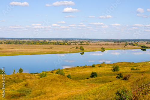 Beautiful river and yellow meadow under the summer sky