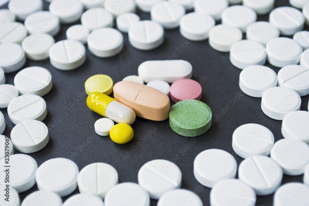 Colourful pills surrounded by white round pills Colourful pills surrounded by white round pills
