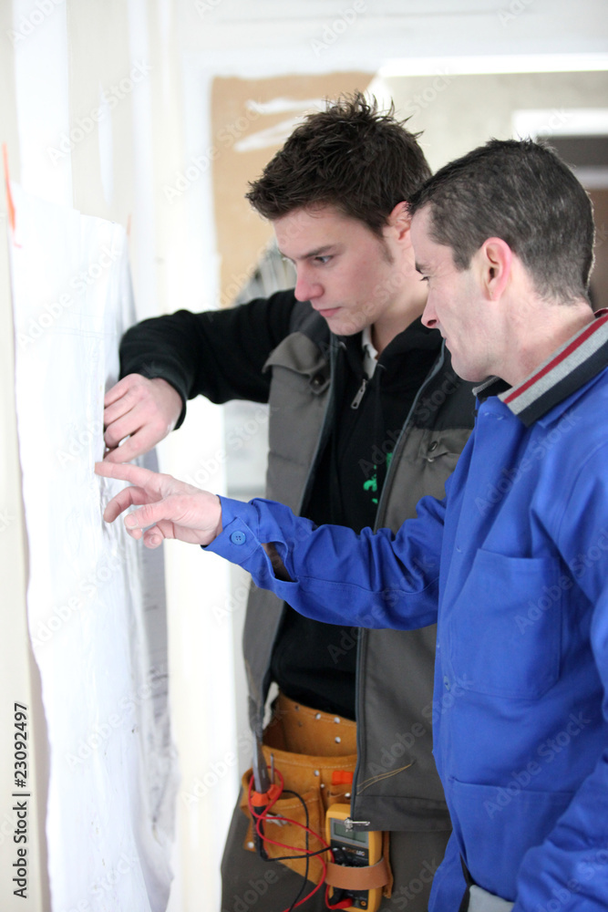 Obraz premium Ouvriers devant plan de chantier