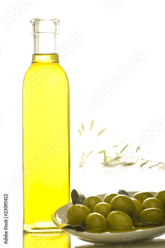 A bottle of olive oil with olives on white background