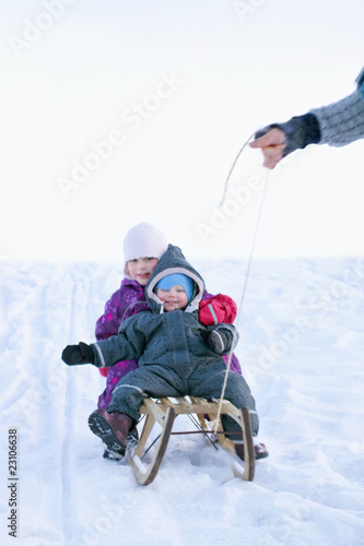 Winter joy - Small children in sledge during snow pulled by a ma