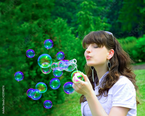 Young girl blowing soap bubbles in spring green park