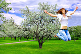 jumping pretty girl with open hands in spring rural park