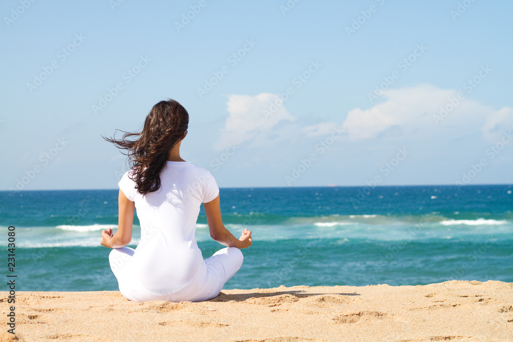 back view of woman meditating on beach back view of woman meditating on beach