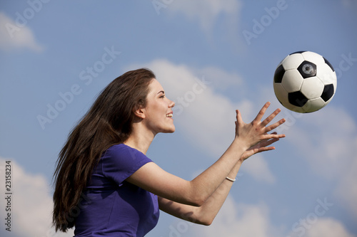 lächelnde hübsche junge Frau fängt Fussball