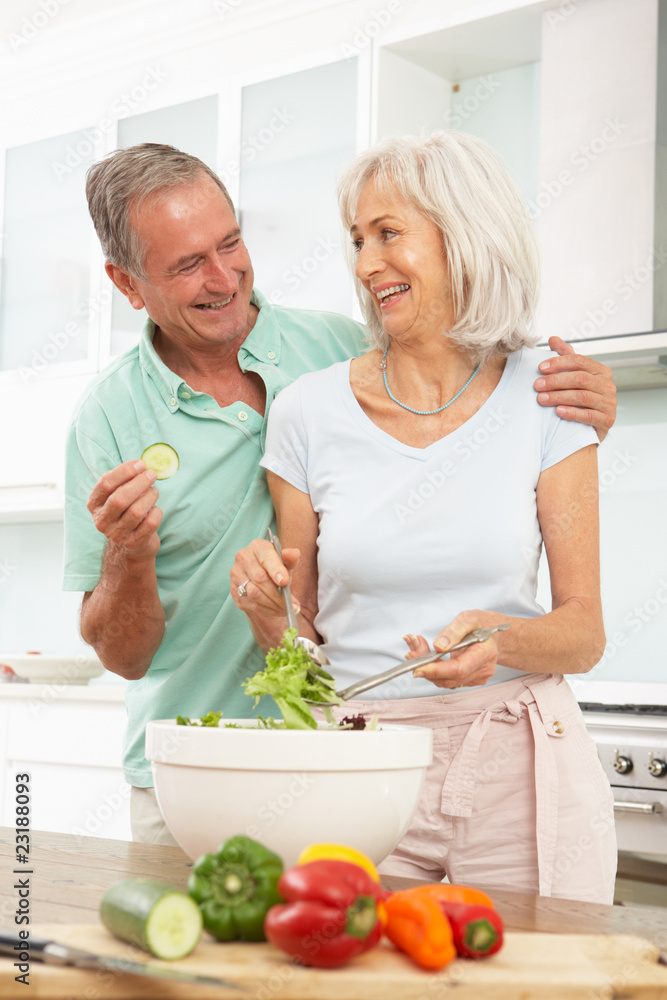 Senior Couple Preparing Salad In Modern Kitchen