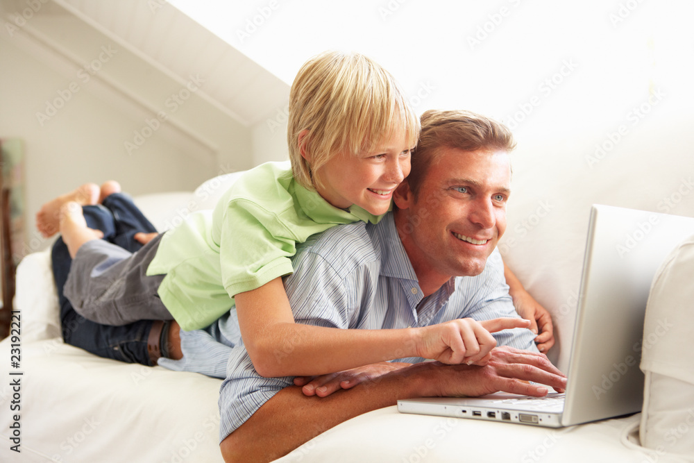 Father And Son Using Laptop Relaxing Sitting On Sofa At Home Father And Son Using Laptop Relaxing Sitting On Sofa At Home
