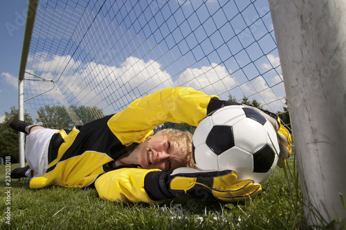 junge blonde Frau im Fussballtor fängt ball