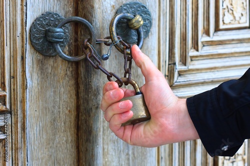 Hand holding old iron security lock of ornamental wooden door