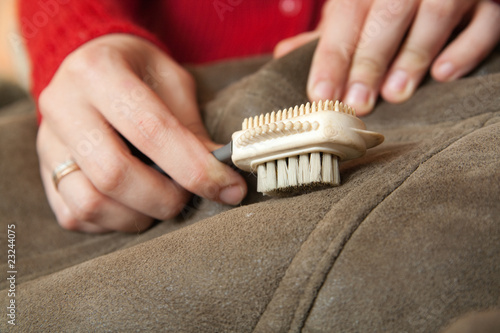 Woman cleaning a sheepskin with whisk broom photo