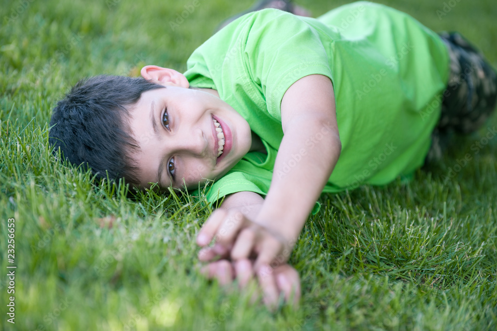 Happy boy in green lying on the green glade Happy boy in green lying on the green glade