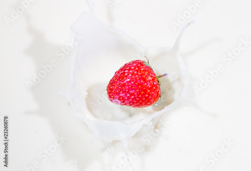 Fresh strawberry splashing into milk