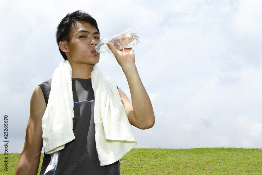 A young Asian man drinking after a work-out A young Asian man drinking after a work-out