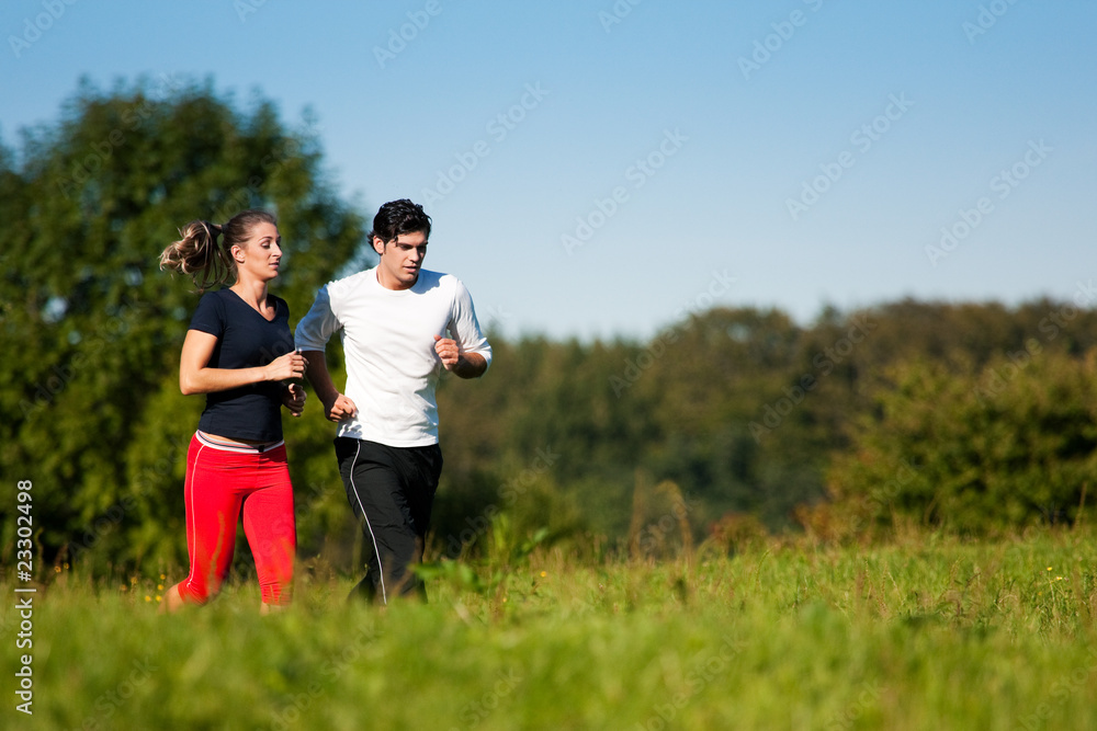 Sport-Paar joggt auf Wiese im Sommer Sport-Paar joggt auf Wiese im Sommer