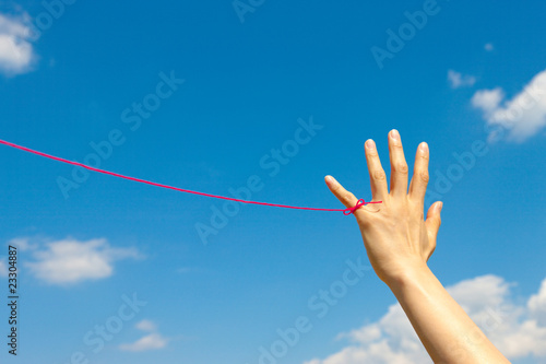 青空と女性の小指に赤い糸 photo