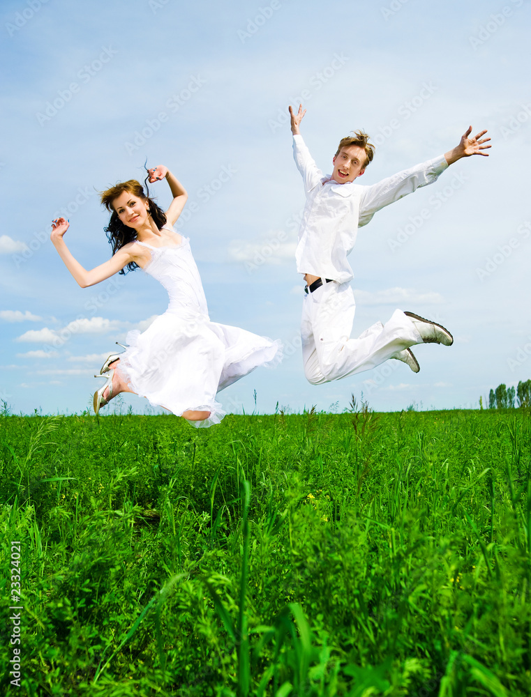 Couple jump in a meadow