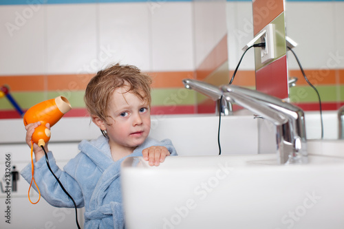 kleiner junge föhnt sich die haare photo