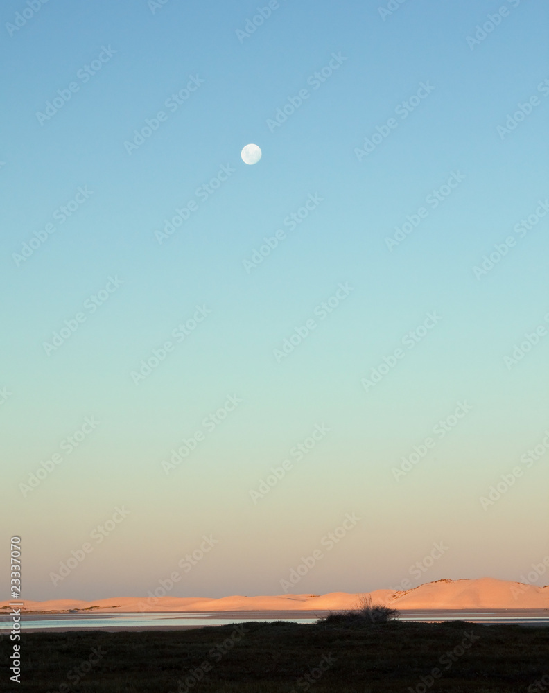 Moon rising over a lagoon in the late afternoon